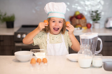 Wall Mural - Child chef cook with eggs. Child chef cook prepares food at kitchen. Kids cooking. Teen boy with apron and chef hat preparing a healthy meal.