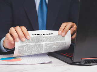 Businessman tearing up a contract agreement while sitting at a desk.