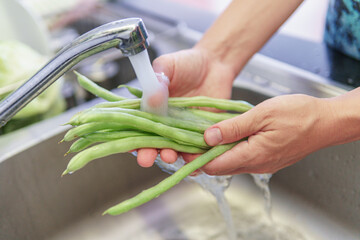 Woman hands washing fresh green beans in a kitchen