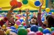 children in a ball pit, tossing colorful balls up