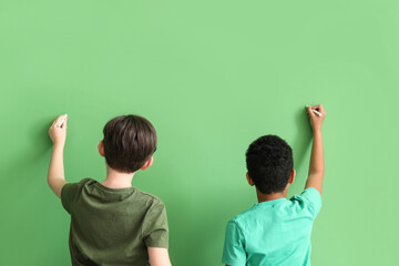 Canvas Print - Little boys drawing with chalk pieces on green background, back view. Children's Day celebration