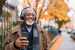 African old man is listening to music on smartphone with headphones outdoors
