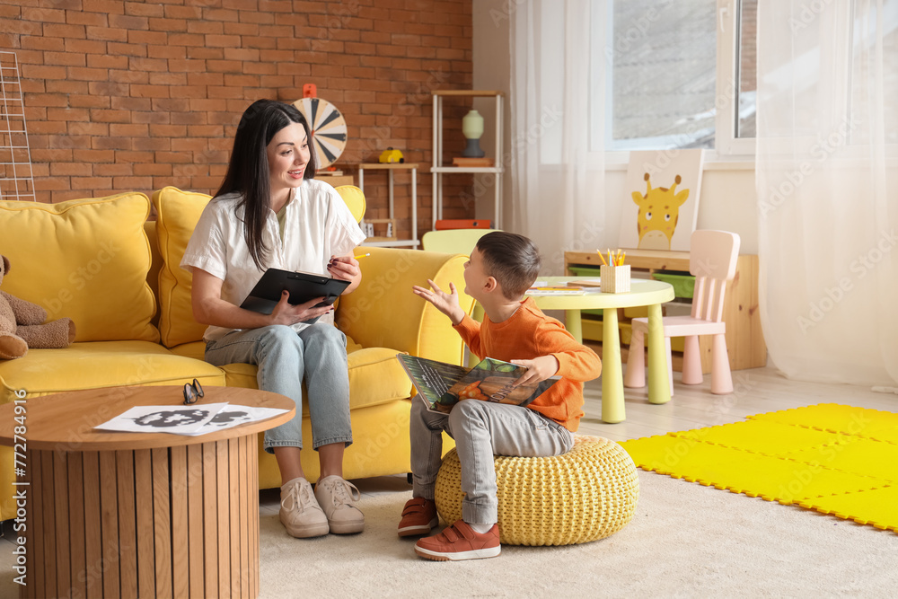 Female psychologist with little boy reading book in office