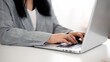 © bongkarn - A cropped image of a businesswoman working or browsing on the laptop, working in a modern office.