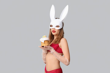 Wall Mural - Sexy young woman in bunny mask with Easter cake on white background