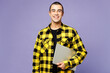 Young fun smiling happy smart IT middle eastern man wear yellow shirt casual clothes hold use work on laptop pc computer isolated on plain pastel purple background studio portrait. Lifestyle concept.
