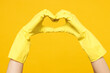 © ViDi Studio - Close up cropped photo shot woman wear purple shirt rubber gloves do housework tidy up showing shape heart with hands heart-shape sign isolated on plain yellow background studio. Housekeeping concept.