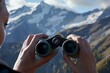 closeup of hands adjusting binocular focus, mountains backdrop