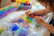kid crafting with bubble wrap, colorful paints applied
