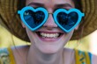 blue heartshaped sunglasses worn by a smiling person