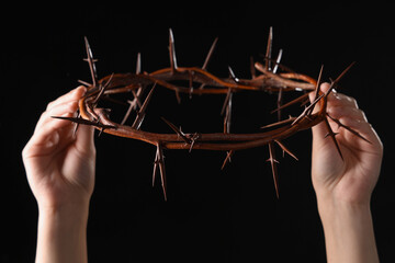 Wall Mural - Female hands with crown of thorns on black background. Good Friday concept