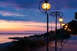 street lanterns illuminating a beachfront path at dusk