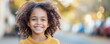 Smiling little African American child on blurry street background portrait. Cute immigrant offspring walks in city. Black kinky haired girl.