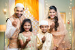 Happy smiling indian couple with kid wishing for ramadan festival by saying hand gesture while looking at camera at home - concept of greeting, family bonding and festival celebration