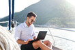 Working in travel. Man on yacht with laptop. Sea vacation on sailboat with insurance. Traveler using computer, Internet. Freelancer office workplace in calmness, silence. Successful business lifestyle