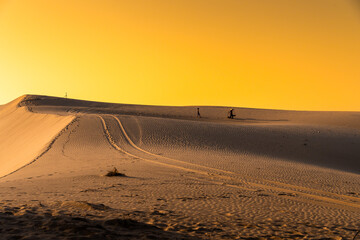 Wall Mural - Aerial view of a peasant woman carries a bamboo frame on the shoulder across sand dunes in Ninh Thuan province, Vietnam. It is one of the most beautiful places in Vietnam