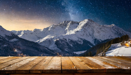 Wall Mural - Empty wooden deck table against view of snowy mountain range in the night.