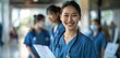 © Divine123victory - Asian nurse smiling while standing in the hospital hallway with medical team. Blurred background, female student holding clipboard and stethoscope.