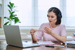 © Valerii Honcharuk - Young female college student in headphones studying using laptop computer for video chat