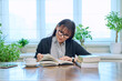 © Valerii Honcharuk - Middle-aged woman reading books, sitting at table at home