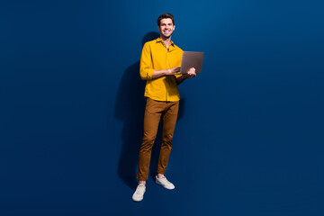 Poster - Full length photo of nice young male hold netbook work remotely dressed stylish yellow garment isolated on dark blue color background