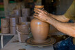 Crop potter shaping clay vase on wheel in workshop