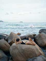 Sticker - Sensual Summer Beauty: Attractive Woman in Sexy Swimwear Posing on Beach Rocks.