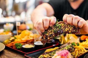 Wall Mural - person holds a deliciously garnished rib over a tray of assorted dishes, showcasing a vibrant and appetizing meal