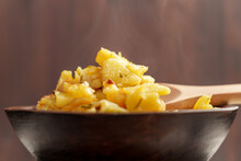 Hot Roasted Sliced Potatoes Ready To Eat In Wooden Bowl With Rustic Spoon
