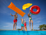 Fototapeta  - Family enjoys pool fun with floaties throw them in the air