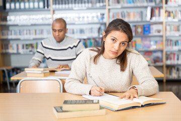 Wall Mural - Portrait of young adult woman studying in at public library