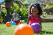 A young girl with a beaming smile plays with colorful balls on a sunny lawn, radiating joy and energy. AI Generated.