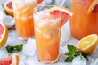 Homemade red grapefruit lemonade in glass with sliced grapefruit and ice rocks
 