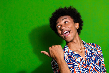 Poster - Portrait of interested man wearing print shirt pointing finger billboard excited give tips for beginners isolated on green color background