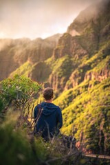 Canvas Print - Man perched atop a grassy hill, taking in the view of the vast valley below