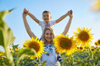 Happy mother and son in Ukrainian clothes - embroiderers in a field of sunflowers.
