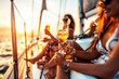 Group of friends relaxing on luxury yacht, drinking cocktails and having fun together while sailing in the sea