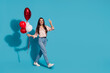 © deagreez - Full length photo of lovely girl wear silk blouse hold heart balloons go empty space show v-sign isolated on blue color background