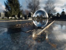 A Glass Ball Is Sitting On A Grave Marker. The Reflection Of The Ball In The Water Creates A Sense Of Depth And Mystery