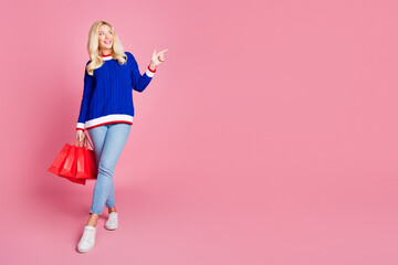 Poster - Full size photo of pretty lady hold bags indicate finger empty space wear blue sweater isolated on pink color background