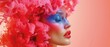   A woman's face is adorned with pink and blue makeup Her hair forms a frill of pink and blue hues