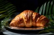 Hearty croissant on a palm leaf plate against a polished metal background