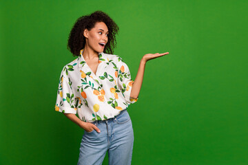 Sticker - Photo of adorable impressed woman dressed print shirt showing arm looking empty space isolated green color background