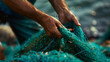 Close-up view of a man hands picking up a green fishing net. Waste in nature. Environmental Protection