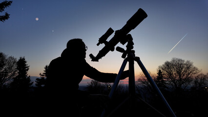 Wall Mural - amateur astronomer looking at the evening skies, observing planets, stars, moon and other celestial 