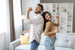© Home-stock - Joyful indian couple dancing in living room interior, having fun and singing, husband and wife enjoying spending time together