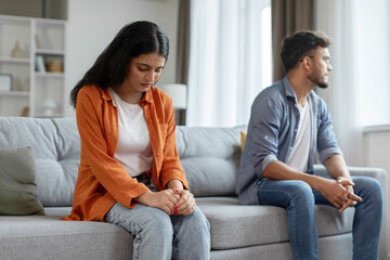 Crisis in relationships. Upset indian couple sitting on couch dont talk to each other after fight, home interior