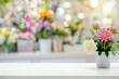 Flower shop background blur, white table top with colorful flowers in vases on the right side of the picture. Exquisite floral display and natural beauty for decoration or product presentation mockup