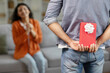 Husband congratulating hindu wife, holding wrapped present box behind back celebrating romantic holiday or birthday, selective focus