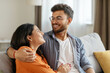 © Home-stock - Loving indian spouses hugging, sitting on sofa at home, enjoying spending weekend together. Romantic relationship and love concept